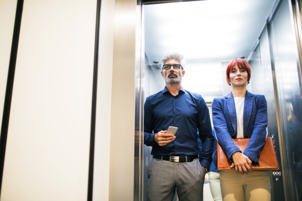 Two business people in the elevator in modern office building.