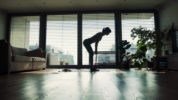 Beautiful young fitness woman doing exercise at home in the evening.