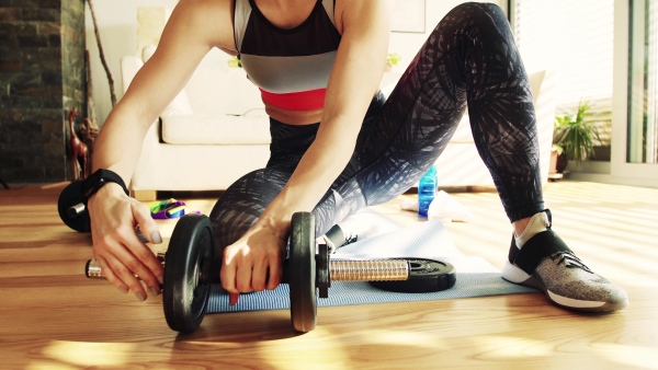 An unrecognizable young woman getting ready for exercise at home.