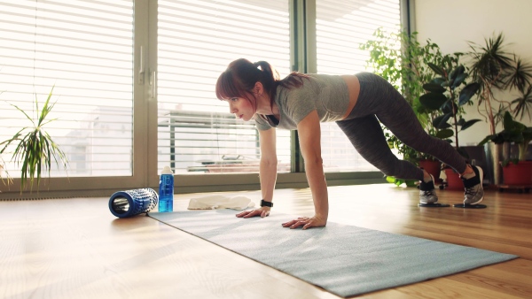 Beautiful young fitness woman doing exercise at home.