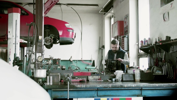 Mature man mechanic repairing a car in a garage.