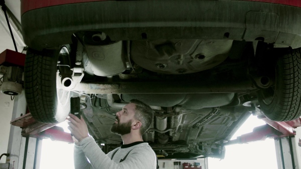 Mature man mechanic repairing a car in a garage.