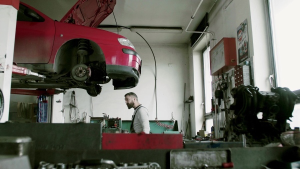 Mature man mechanic repairing a car in a garage. CLose up.