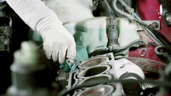 Unrecognizable man mechanic repairing a car in a garage.