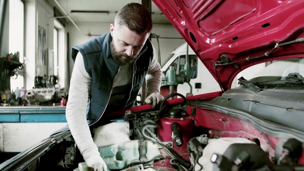 Mature man mechanic repairing a car in a garage.