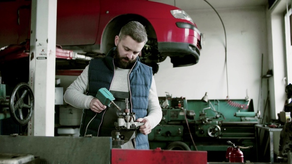 Handsome man mechanic repairing a car in a garage.