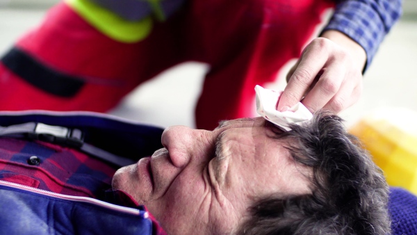 Accident of a male worker at the construction site. An unrecognizable man helping his injured colleague. Close up.