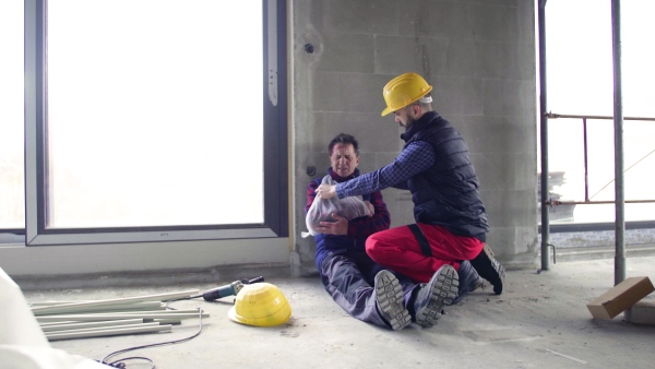 Accident of man workers at the construction site. A builder with a broken arm.