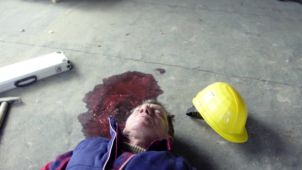 Accident of a male worker at the construction site. A man lying unconscious on the floor. Close up.