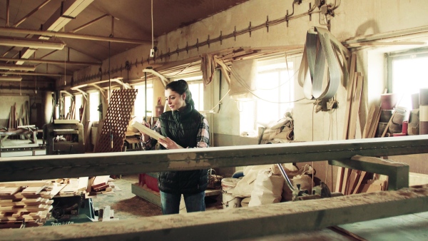 Portrait of a young woman worker in the carpentry workshop, working with wood.