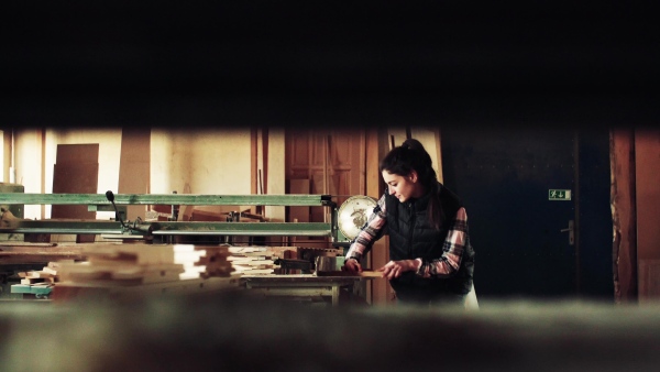 Portrait of a young woman worker in the carpentry workshop, working with wood.