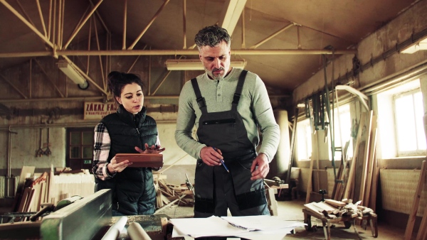 Portrait of a man and woman workers with a tablet in the carpentry workshop, planning.