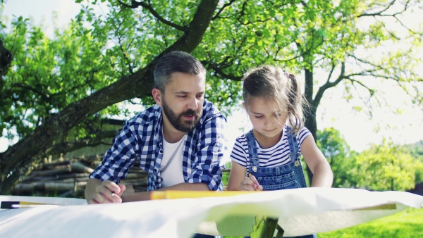 Father with a small daughter outside, planning a wooden birdhouse or bird feeder. Sketches making.