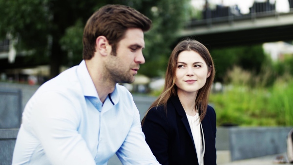 A man insurance agent talking to an unrecognizable woman outside on the road after a car accident.