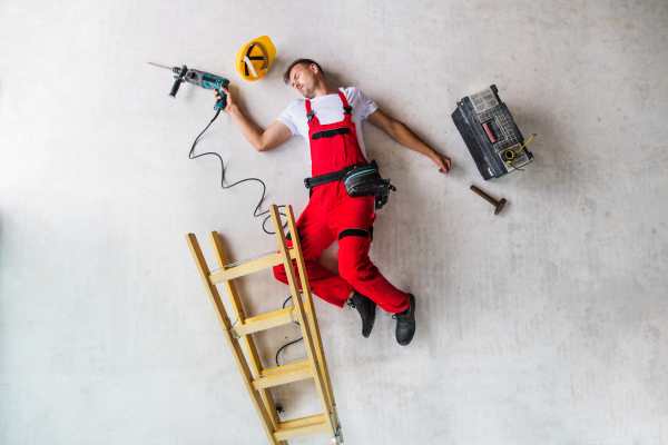 Accident of a male worker at the construction site. An injured man on the floor. Top view.