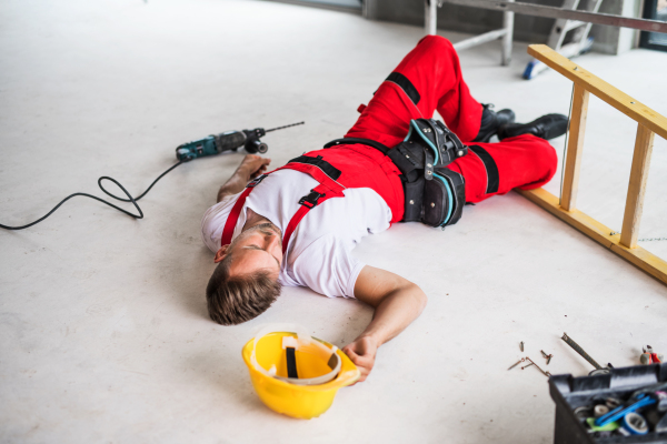 Accident of a male worker at the construction site. An injured man lying unconscious on the floor.