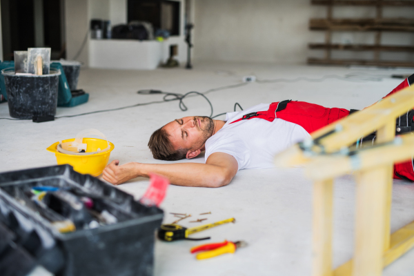 Accident of a male worker at the construction site. An injured man lying unconscious on the floor.