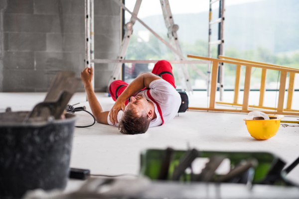 Accident of a male worker at the construction site. An injured man on the floor.