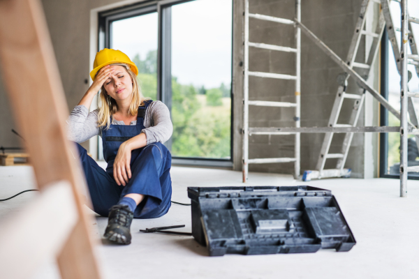 Accident of a female worker at the construction site. A woman with an injured head sitting on the floor.