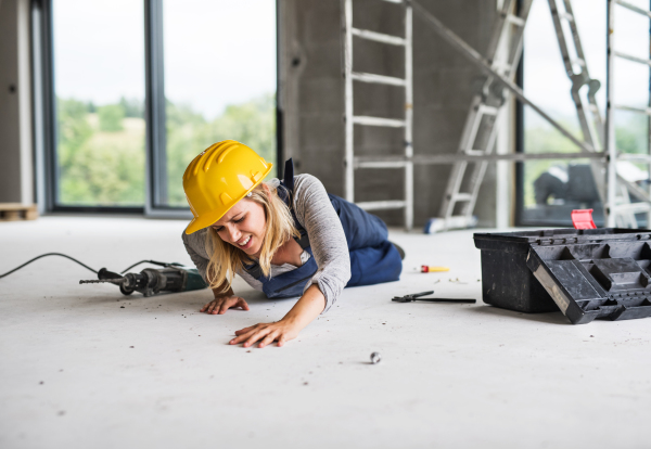 Accident of a female worker at the construction site. An injured woman on the floor.