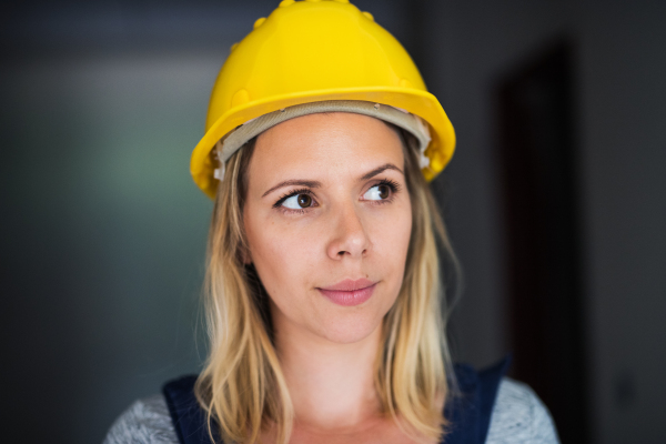 Portrait of a female worker on the construction site. Close-up of a beautiful young woman with a yellow helmet.