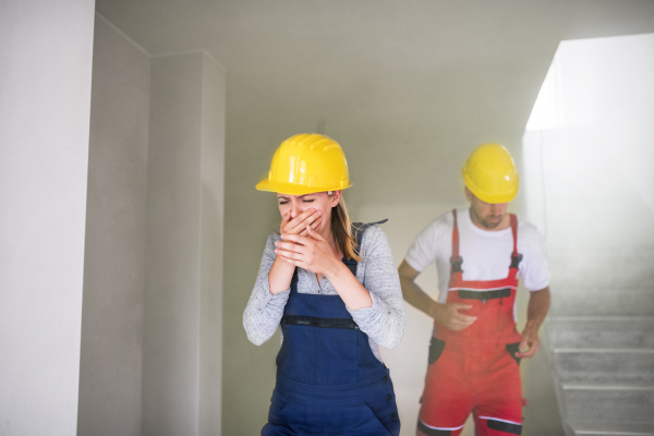 Woman and man workers running from the construction site, coughing and covering face.