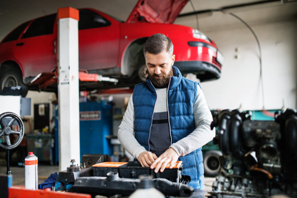 Mature man mechanic repairing a car in a garage.