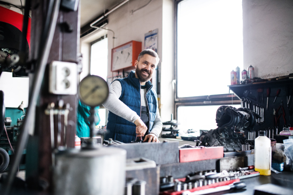 Mature man mechanic repairing a car in a garage.