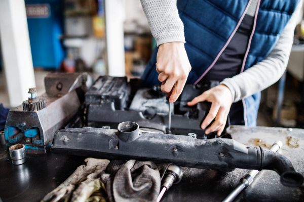 Unrecognizable man mechanic repairing a car in a garage.