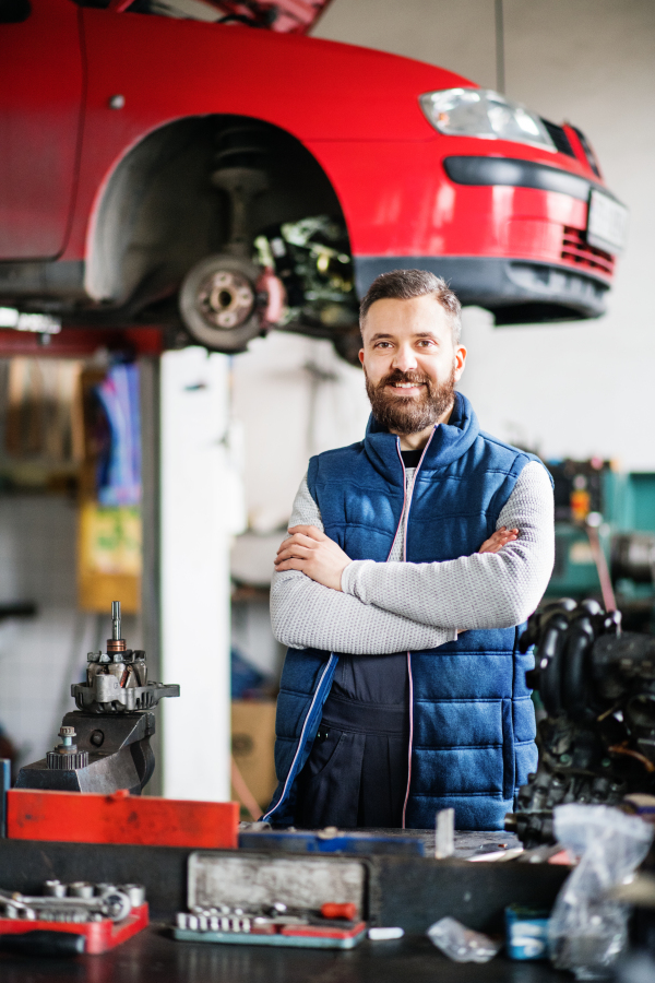 Portrait of a man mechanic in a car garage, arms crossed.