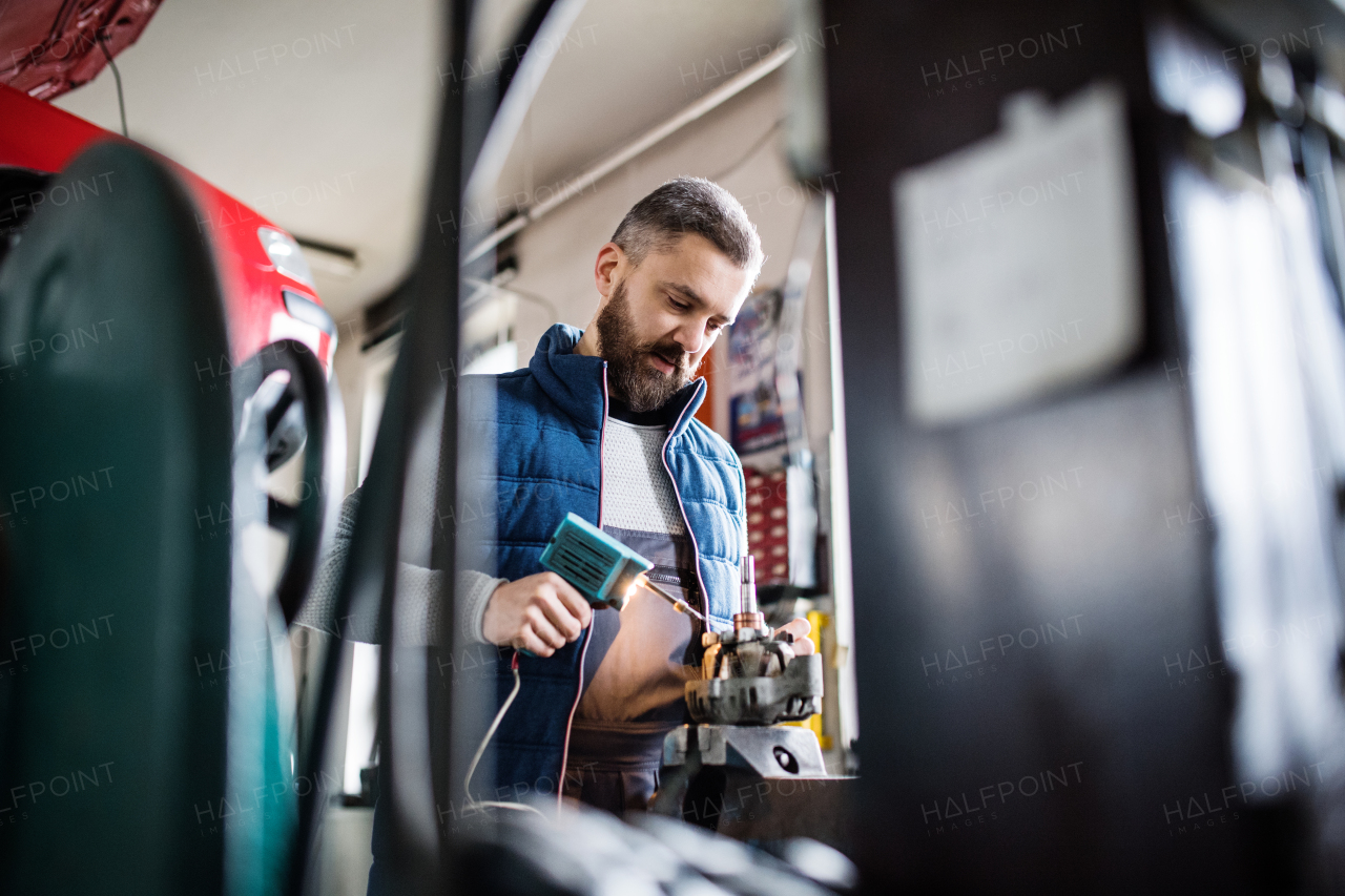 Handsome man mechanic repairing a car in a garage.