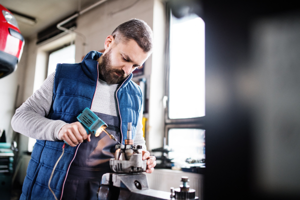 Handsome man mechanic repairing a car in a garage.