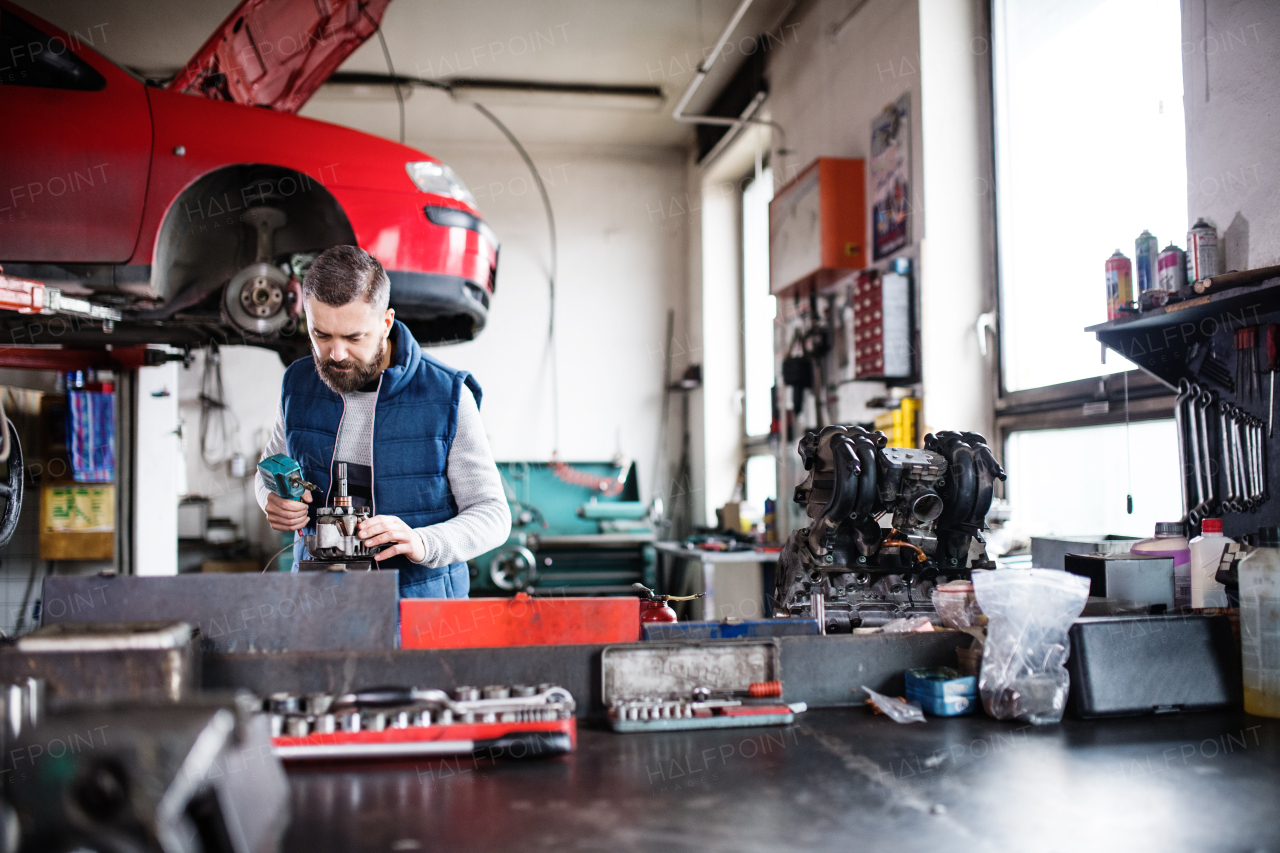 Mature man mechanic repairing a car in a garage.