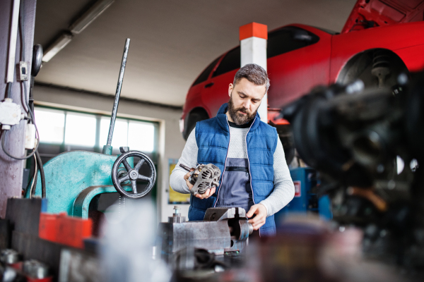 Mature man mechanic repairing a car in a garage.