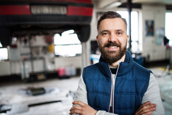 Portrait of a man mechanic standing in a garage, arms crossed.