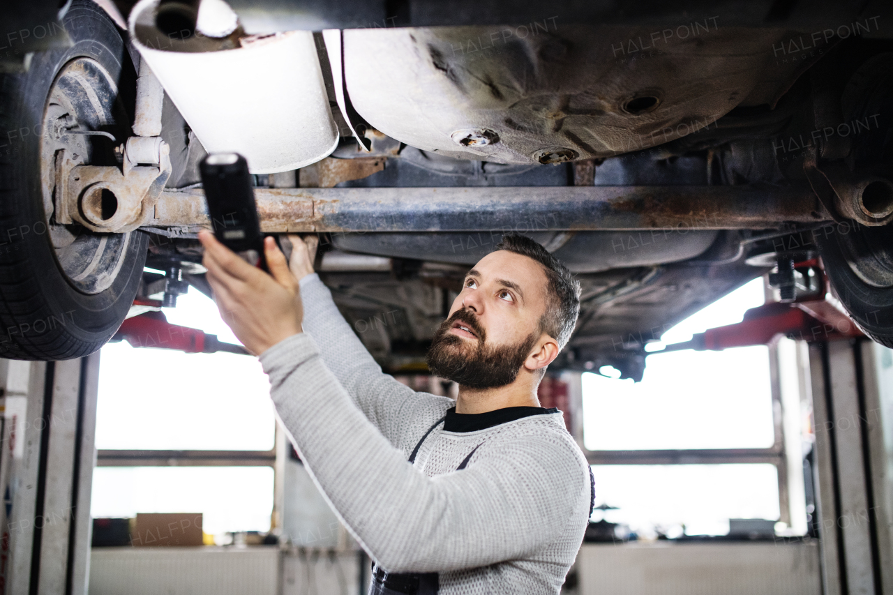 Mature man mechanic repairing a car in a garage.