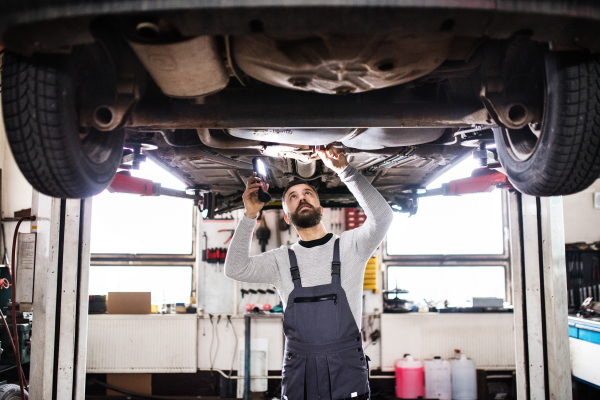 Mature man mechanic repairing a car in a garage.