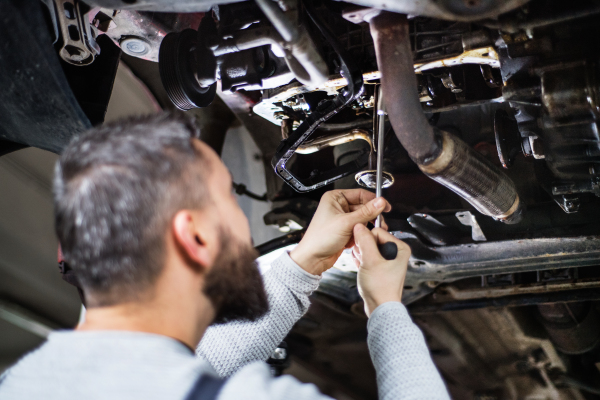 Mature man mechanic repairing a car in a garage. CLose up.