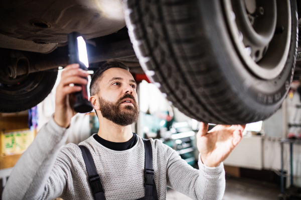 Mature man mechanic repairing a car in a garage.