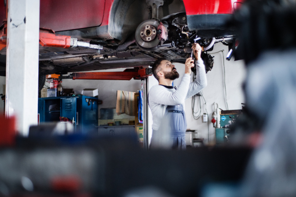 Mature man mechanic repairing a car in a garage.