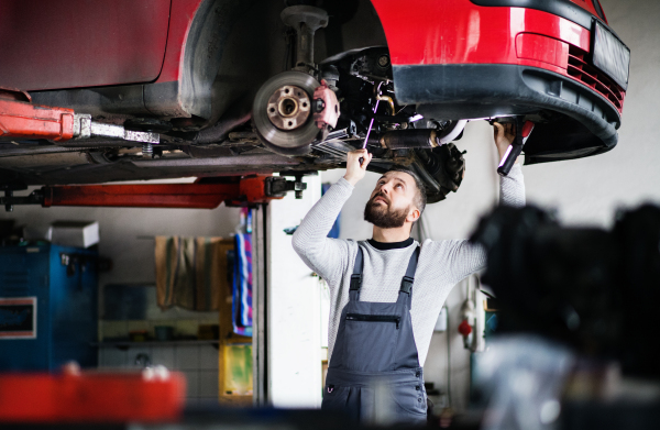 Mature man mechanic repairing a car in a garage.