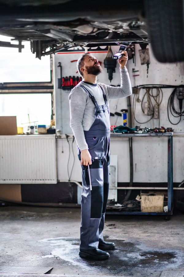 Mature man mechanic repairing a car in a garage.