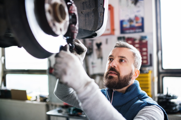 Mature man mechanic repairing a car in a garage.