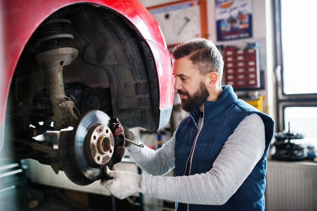 Mature man mechanic repairing a car in a garage.