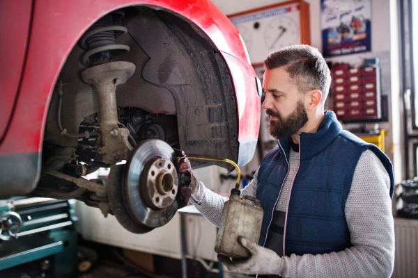 Mature man mechanic repairing a car in a garage.