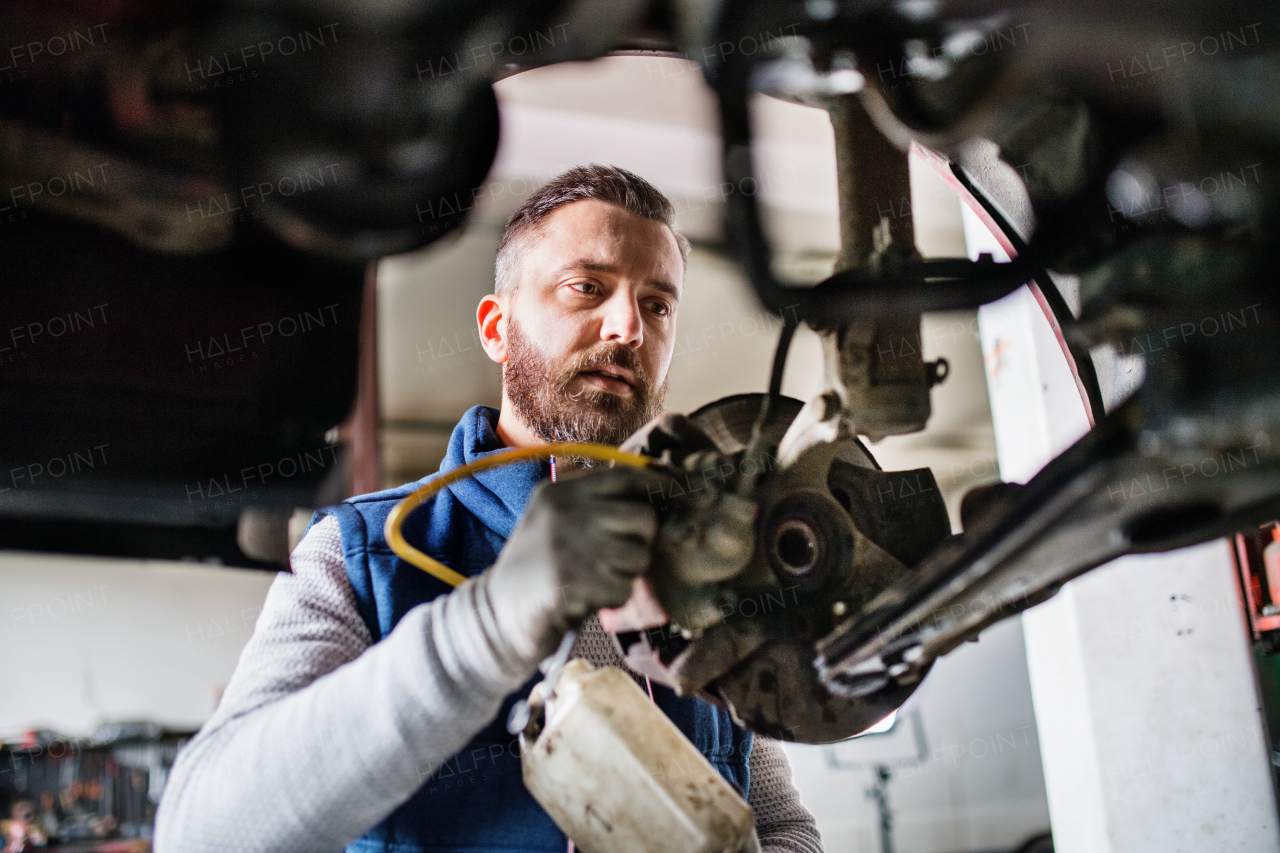 Mature man mechanic repairing a car in a garage.