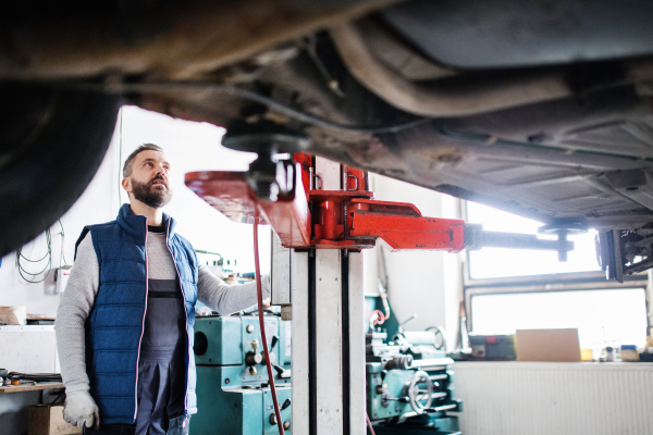 Mature man mechanic repairing a car in a garage.