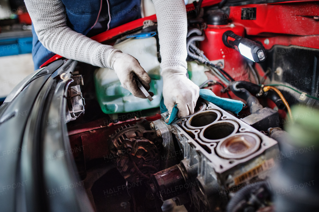 Unrecognizable man mechanic repairing a car in a garage.