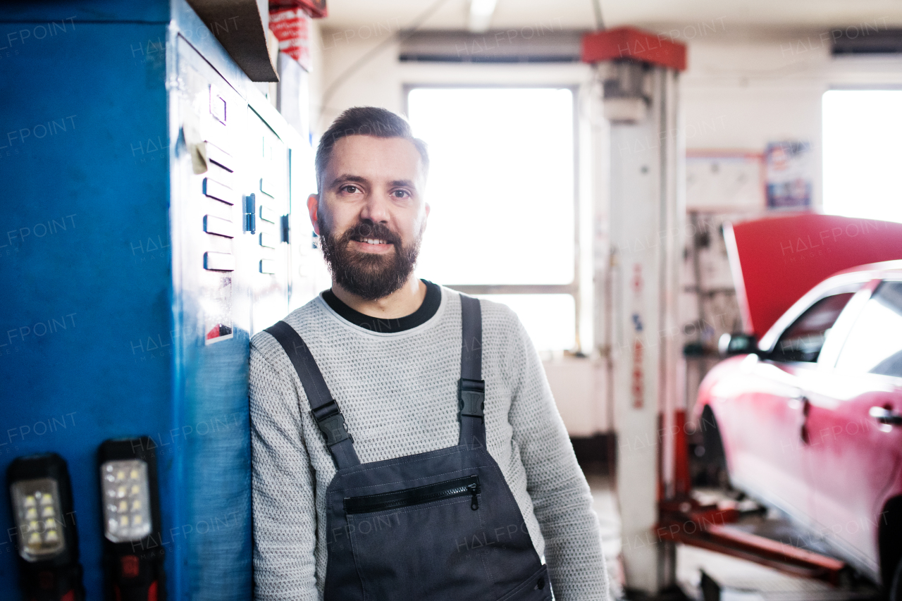 Portrait of a man mechanic standing in a garage.