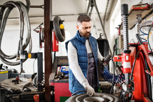 Mature man mechanic repairing a car in a garage.